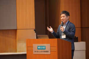 多士済々倶楽部【関東】定例会でマイクを手に講演する当社代表